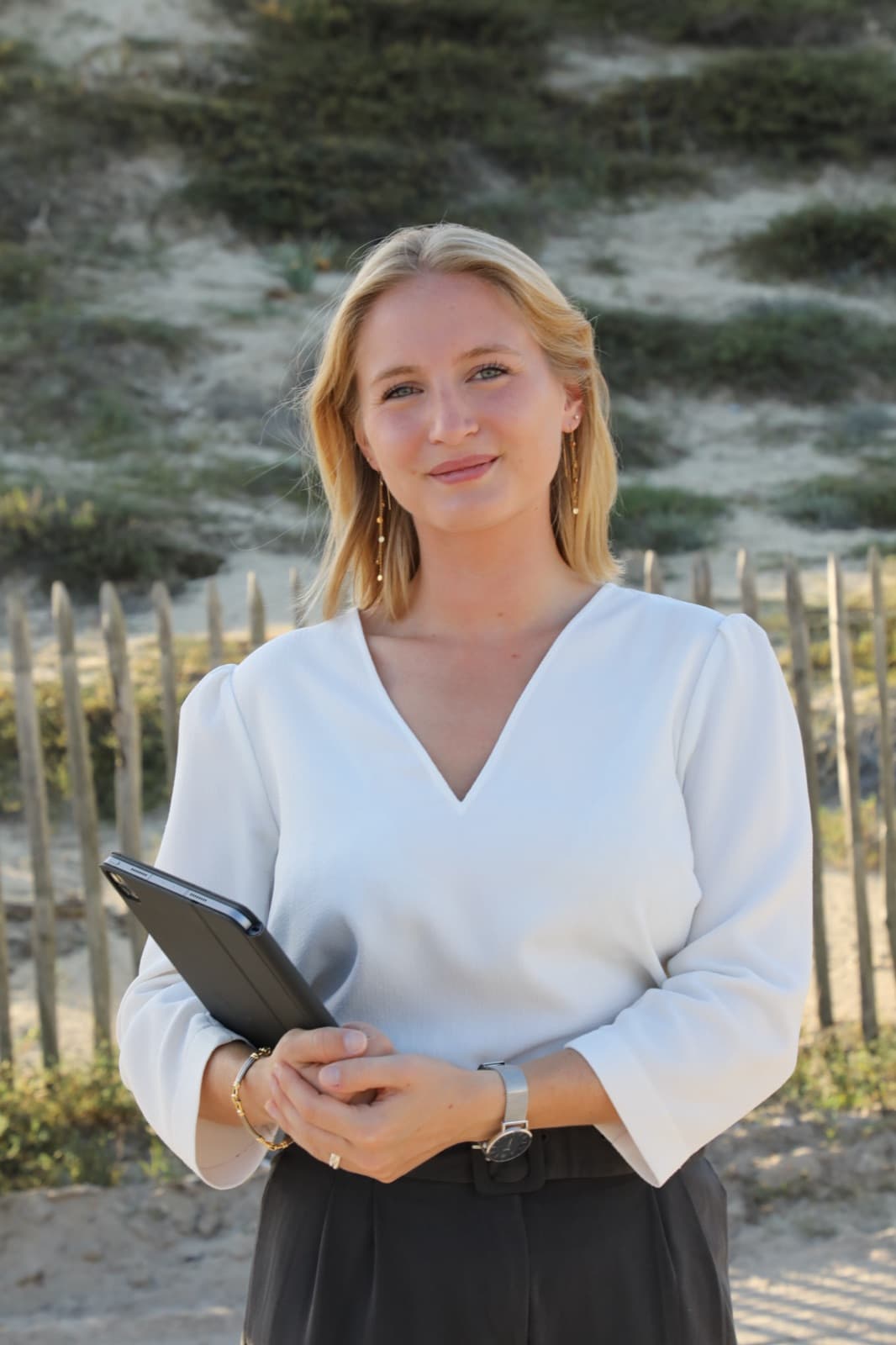 Charlotte, cofondatrice de Green Coast Immobilier, tablette à la main dans les dunes